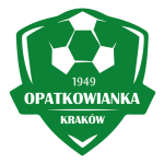 Obrazek przedstawia zielone logo w kształcie tarczy z piłką nożną u góry. W środku widnieje napis „1949 OPATKOWIANKA KRAKÓW”, oznaczający klub sportowy z Krakowa założony w 1949 roku.